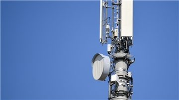 Ein Sendemast für Mobilfunk vor blauem Himmel.
