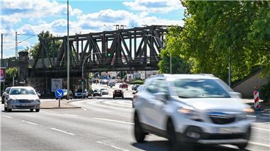 Eisenbahnbrücke über Straße, im Vordergrund Autos.