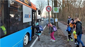 Der Bus für die Grundschüler ist an der Neuenwalder Straße (L120) angekommen. Unter Aufsicht der Eltern steigen die Jungen und Mädchen rasch ein, während die Autos vorbeiziehen. Die Kinder haben diese Bushaltestelle teilweise nach einem längeren Fußweg erreicht.