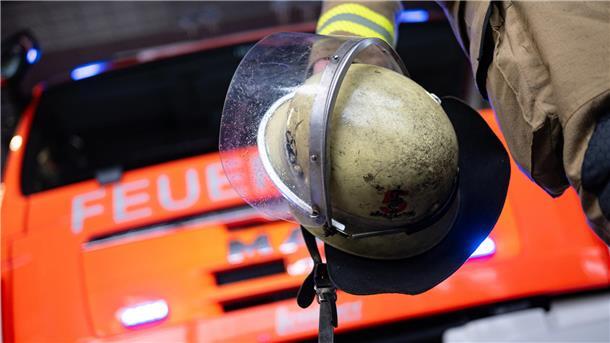 Eine Einsatzkraft der Feuerwehr steht vor einem Einsatzfahrzeug.
