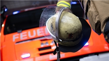 Eine Einsatzkraft der Feuerwehr steht vor einem Einsatzfahrzeug.