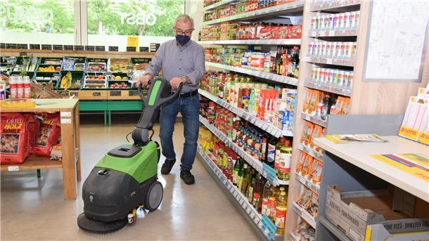 Ein Mann reinigt den Boden eines Supermarktes