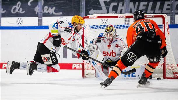 Ein Eishockey-Torhüter und zwei Spieler in Aktion
