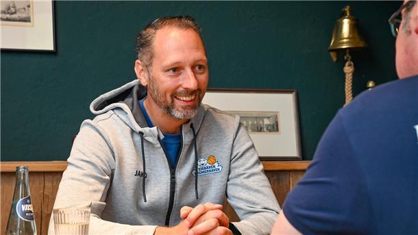 Eisbären-Trainer Esterkamp: „Wir mussten nicht wieder ganz von vorne anfangen.“ Ein Basketball-Trainer lacht, während er ein Interview gibt. Es ist Steven Esterkamp von den Eisbären Bremerhaven.