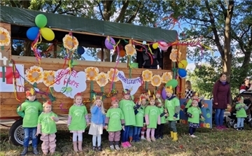 Kinder stehen vor einem mit Luftballons geschmückten Wagen.