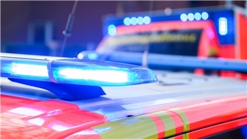 Autofahrer prallt gegen Fassade einer Bankfiliale Blaulichter leuchten an einer Einsatzstelle auf einem Notarztfahrzeug und einem Rettungswagen.