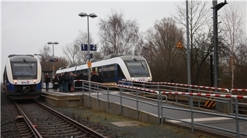 Zwei Züge auf Gleisen an einem Bahnhof.