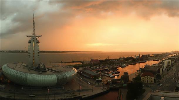 Bremerhaven aus der Luft. Dunkle Wolken treffen auf den Sonnenuntergang.