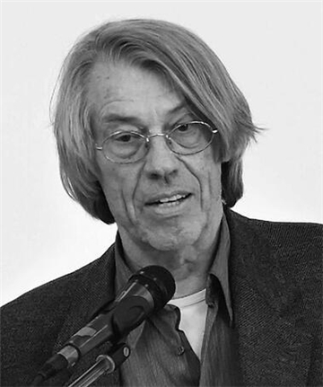 Porträt des Filmemachers, mit Brille und längeren Haaren vor einem Mikrofon sprechend.
