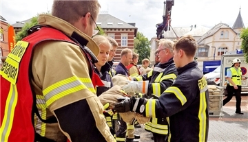 Hochwasserschutztag in Brake: Feuerwehrleute schleppen Sandsäcke.