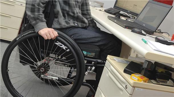 Ein Behinderter im Rollstuhl an seinem Büroarbeitsplatz