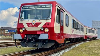 Ein rot-beige lackierter Zug steht auf dem Gleis