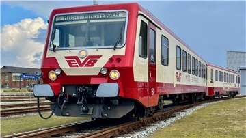 Ein rot-beige lackierter Zug steht auf dem Gleis