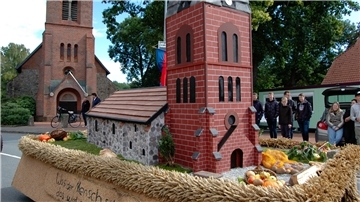 Der Motivwagen der Heeslinger Landjugend rollt an der Kirche vorbei.