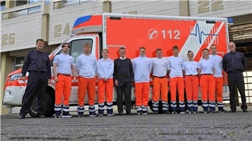 Menschen stehen vor einem Rettungswagen