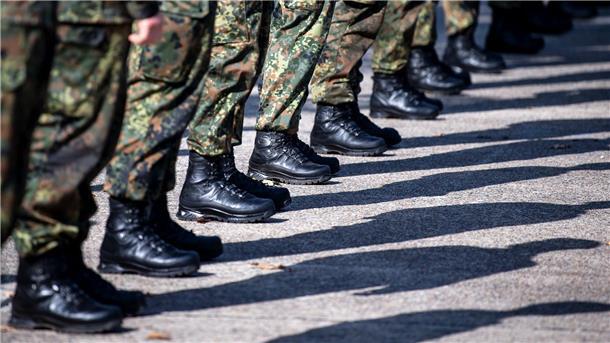 Beine und Füße von Soldaten. Sie stehen auf der Straße, der Bildausschnitt zeigt die militärische Kleidung und Schuhe.