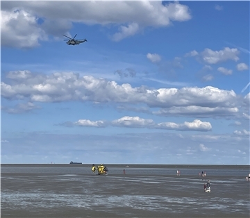 Der Rettungshubschrauber „Christopher 26“ landete im Watt. Darüber kreiste zusätzlich ein Hubschrauber der Bundeswehr.