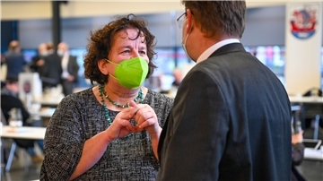 Dr. Susanne Gatti mit grüner FFP2-Maske im Gespräch mit Claudius Kaminiarz von den Grünen