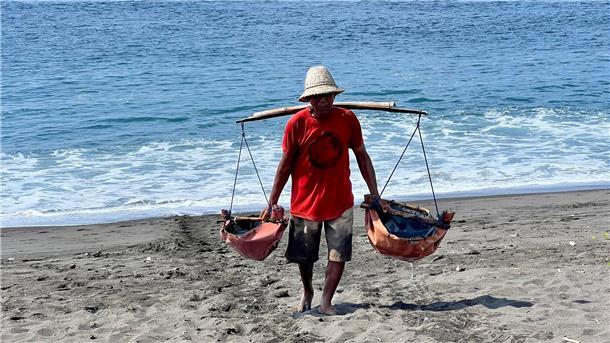 Der Salzbauer Nyoman Warta schleppt Meerwasser an den Strand. Er ist einer der letzten Vertreter dieses Berufs auf der indonesischen Urlaubsinsel.