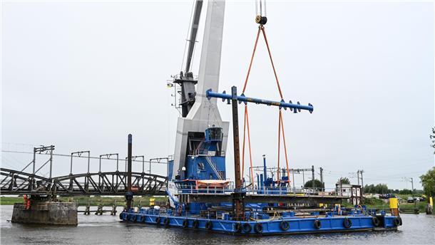Ein Schwimmkran transportiert ein schweres Brückenteil.