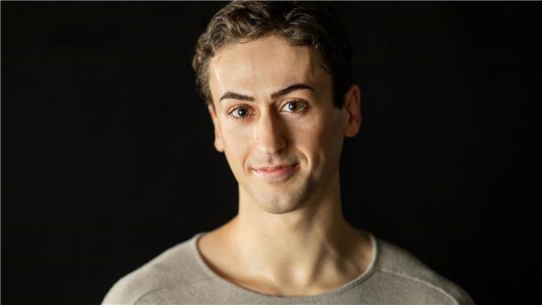 Ein Mann mit kurzen Haaren und dunklen Augen.