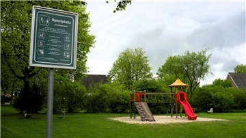 Spielplatz mit viel Rasenfläche, Kletterturm und Rutsche