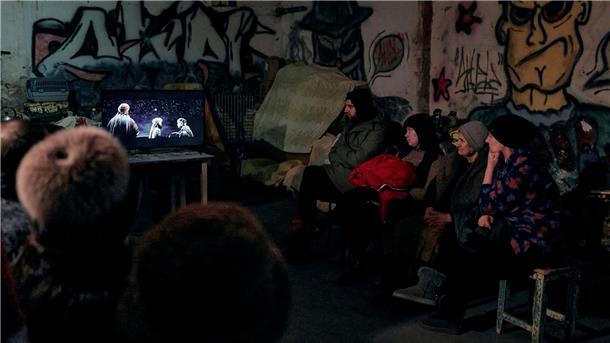 Der Strom kommt von einem Generator: In einem Keller eines Wohnhauses, der als Bunker genutzt wird, schauen sich Menschen einen religiösen Weihnachtsfilm an.