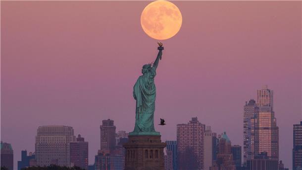 Der Supermond geht hinter der Freiheitsstatue in New York auf.