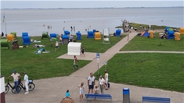 Am Strand von Burhave sind einige Touristen und Strandkörbe zu sehen.