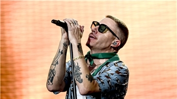 Sänger Macklemore singt bei einem Auftritt vor einer beleuchteten LED-Wand.