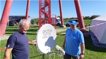 Zwei Männer mit einer Satellitenschüssel.