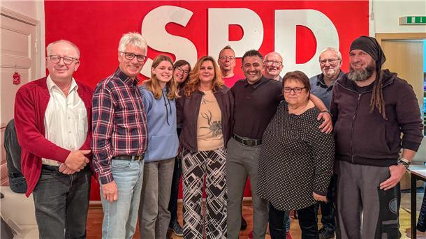 Elf Männer und Frauen stehen nebeneinander vor einer roten Wand mit den weißen Buchstaben "SPD"