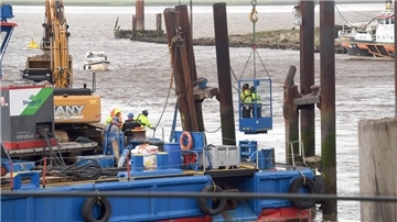 Mit Rüttler und Schwimmkran „Athlet“ ist die Bremerhavener Bergungsfirma BVT angerückt, um einen gelockerten Dalben des Weserfähre-Anlegers wieder stabil zu befestigen. 