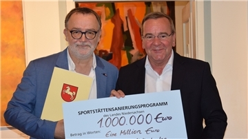 Der Zevener Stadt-Bürgermeister Michael Solty (links) nimmt aus der Hand von Innenminister Boris Pistorius den Zuwendungsbescheid entgegen.
