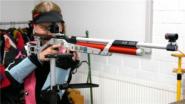 Eine Frau blickt durch das Zielfernrohr eines Sportgewehrs.
