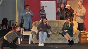Die acht Darsteller des Stücks „Doppelt leben hält besser“ proben das Chaos auf dem Sofa und um das Sofa herum.