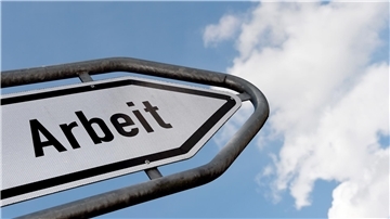 Ein Hinweisschild mit der Auschrift "Arbeit" ragt gen Himmel.