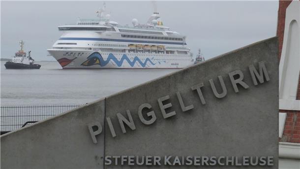 Das Schiff "AIDAaura" fährt im Bildhintergrund auf dem Wasser.