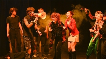 Schülerinnen und Schüler unterschiedlichen Alters spielen gemeinsam auf der Theaterbühne