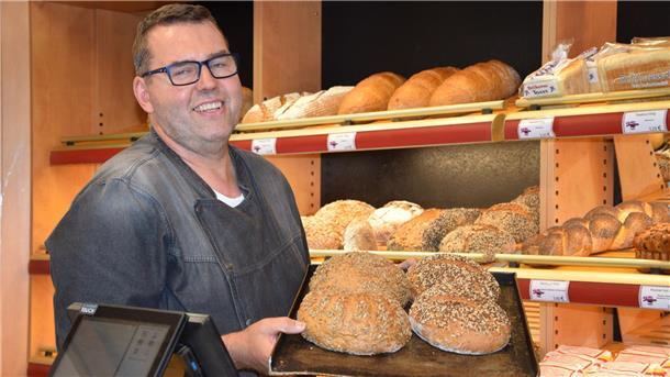 Es zeigt den Bäcker Jantzen. Er hält ein Blech Brot in den Händen.