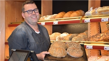 Es zeigt den Bäcker Jantzen. Er hält ein Blech Brot in den Händen.