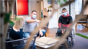 Die Bauherren Yvonne und Marvin Holst schauen mit Raumausstatter Christian Schnakenberg verschiedene Design-Bodenbeläge in Holzoptik an. Foto: Hartmann