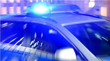 Ein Streifenwagen der Polizei steht mit eingeschaltetem Blaulicht auf der Straße.