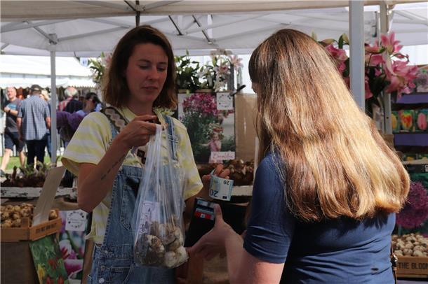 Die Besucherinnen und Besucher decken sich mit den Waren vom Blumenmarkt ein.