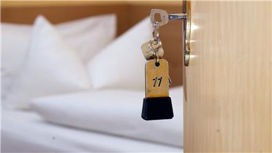 Ein Zimmerschlüssel hängt am 28.11.2014 in einem Gästehaus vor einem Bett im Türschloss.