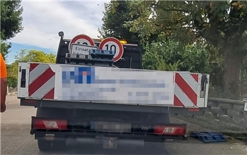 Ein Wagen mit Auflage, auf der Straßenschilder stehen und liegen.