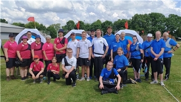 Viele Männer und Frauen in blauen, weißen und roten poloshirts stehen auf dem Rasen.