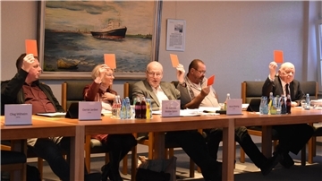 Abstimmung während einer Gemeinderatssitzung in Stadland. Das Foto zeigt die Mitglieder der CDU-Fraktion, die alle mit einer roten Karte gegen ein Vorhaben abstimmen.