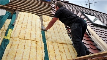 Bild von einem Bauarbeiter bei Arbeiten an einer Dachdämmung
