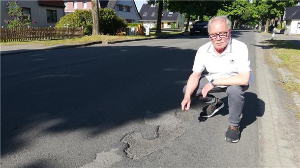 Ein Mann zeigt auf Schlaglöcher